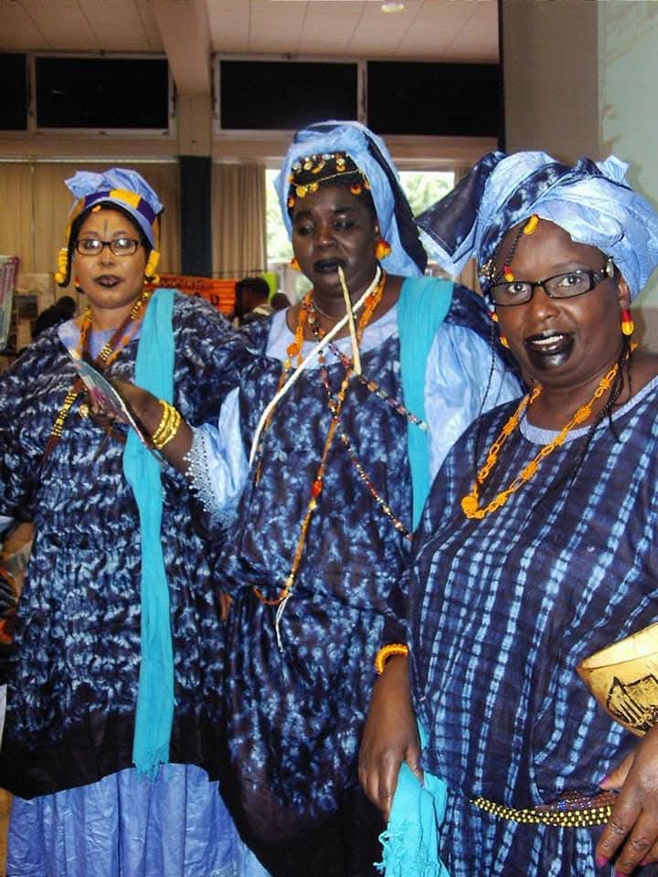Three women in traditional blue tie-dye attire
