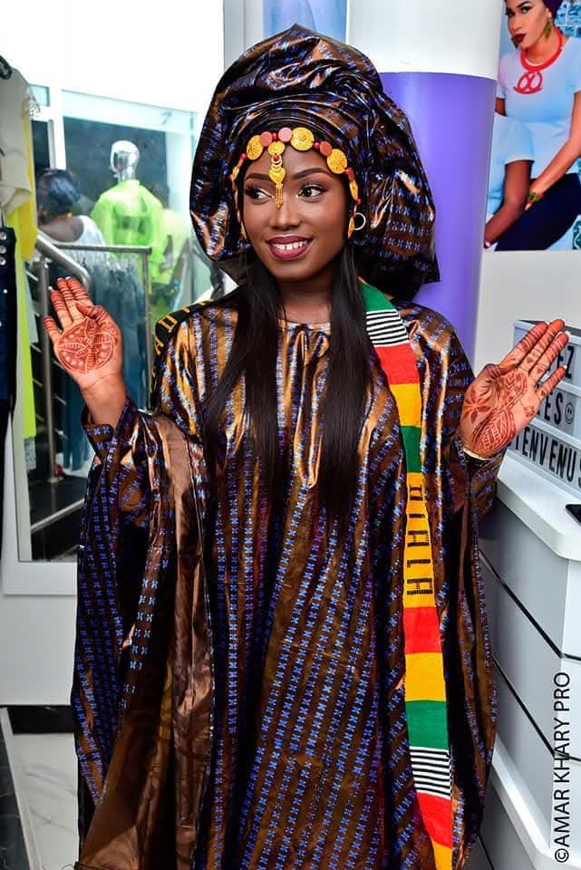 Woman in golden traditional grand boubou with kente sash